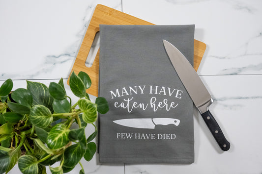 Many Have Eaten Here, Few Have Died Gray Tea Towel with White Ink